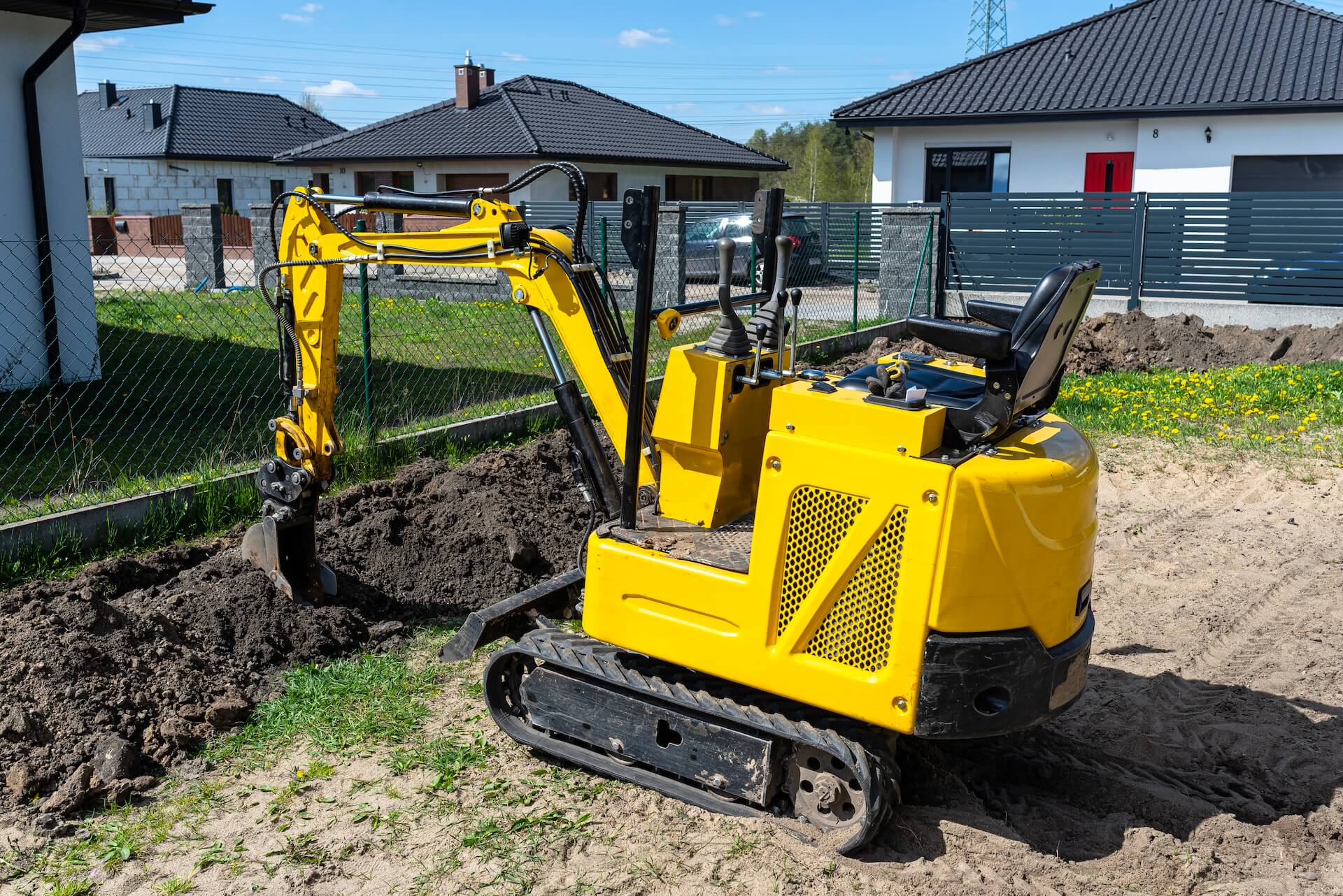 Mini excavator being used in a residential area | Featured image for the What is a Mini Excavator Used For blog on Machinery Direct.