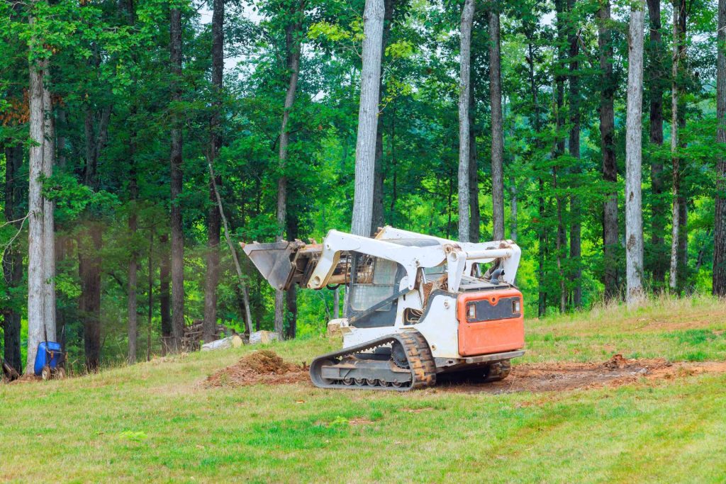 Skid steer working in a forest | Featured image for Skid Steer Uses blog by Machinery Direct.